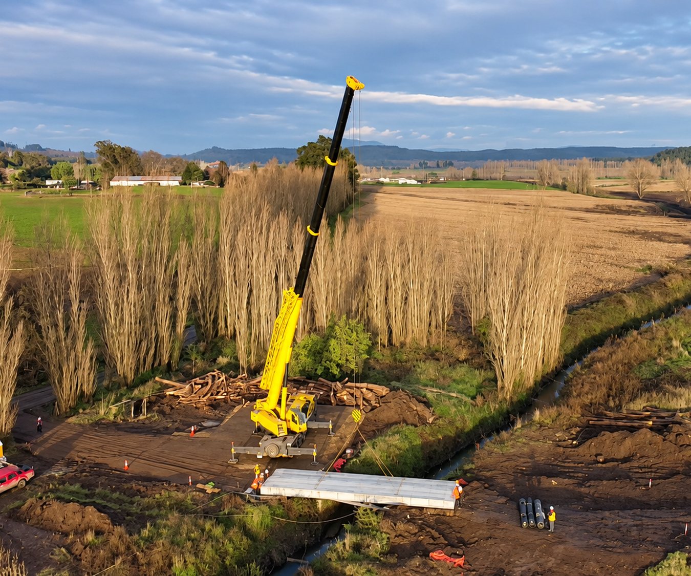 Montaje aéreo de un puente mecano con grúa junto a un canal